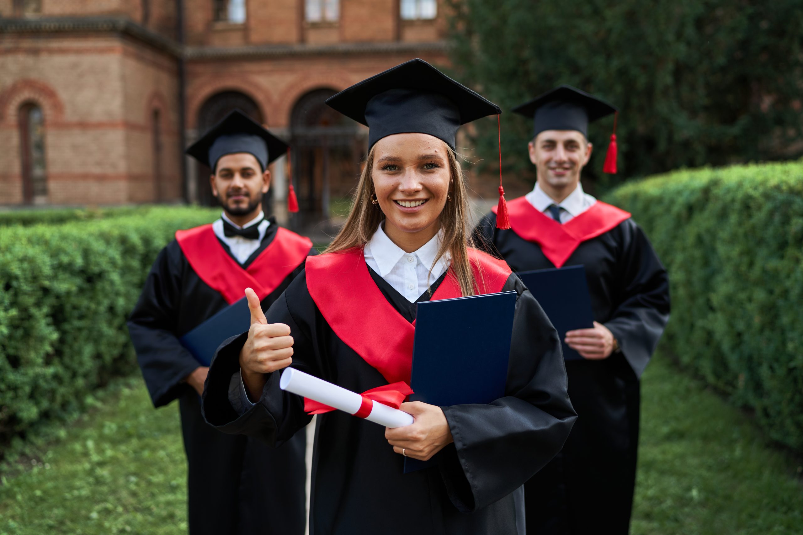 Graduate female shows like with her friends in graduation gowns